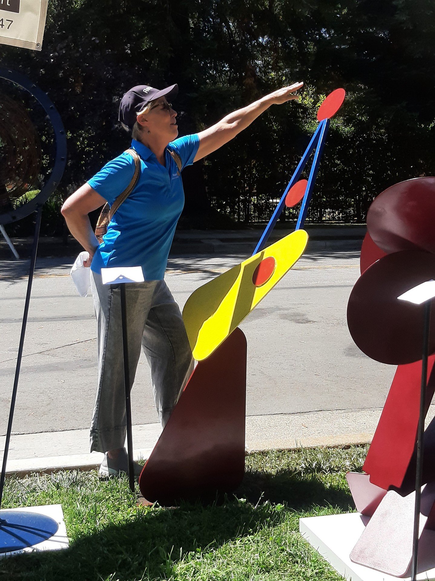Visitor physically interacting with Michael Herold public sculpture at an outdoor art festival, demonstrating curiosity, touch, and real public engagement.