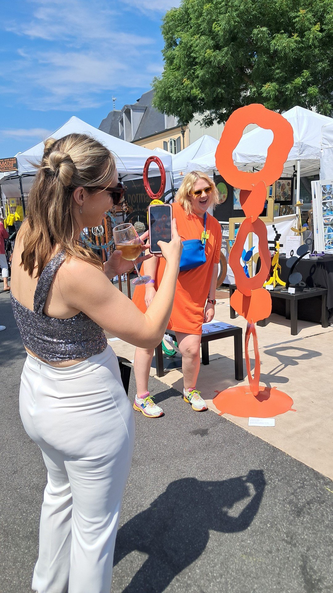 Visitors photographing and interacting with Michael Herold public sculpture at an outdoor art festival, capturing social engagement and shareable public art moments.