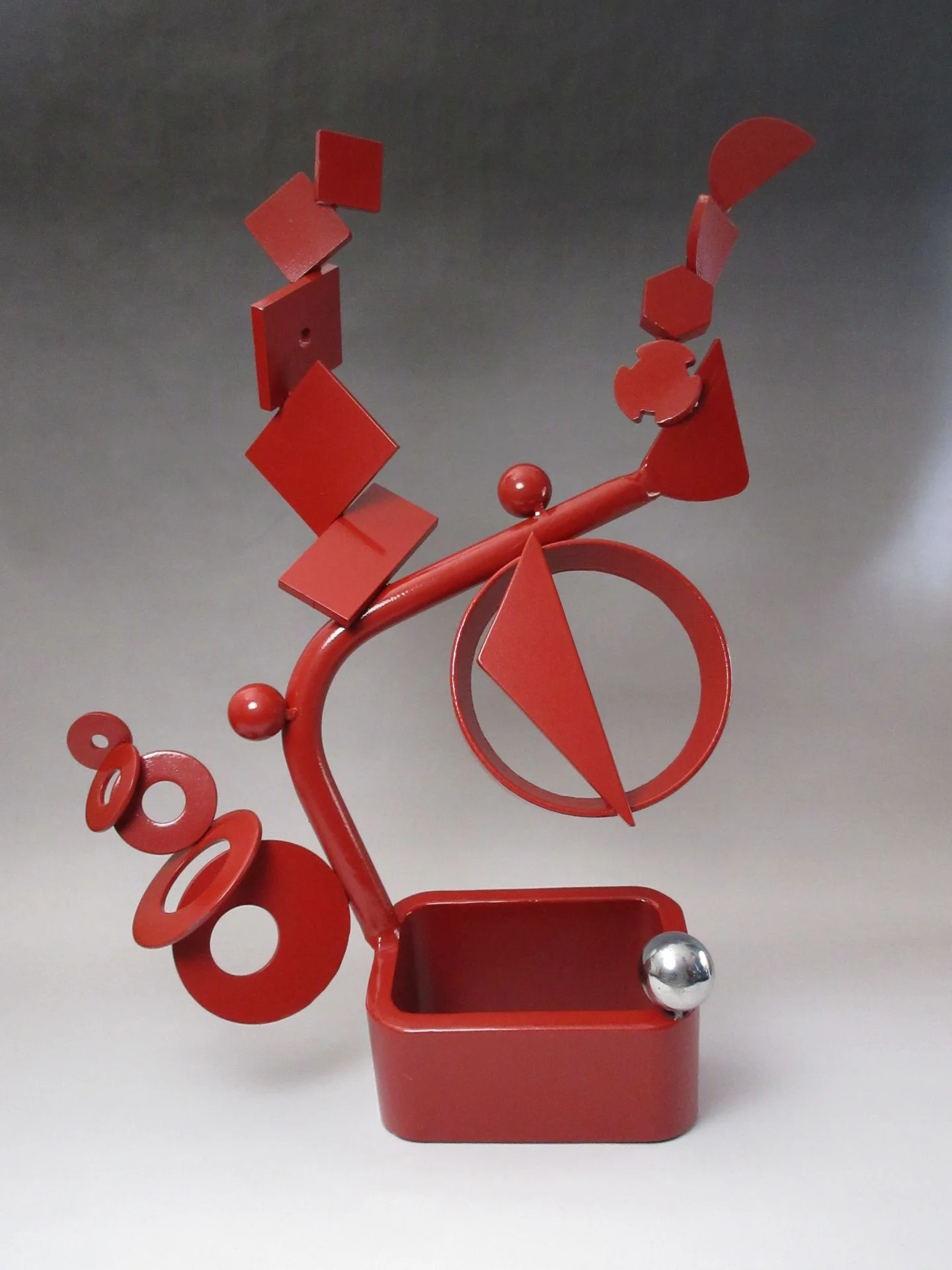 Contemporary red steel sculpture titled “Balancing Act” combining geometric balance, circular forms, and architectural composition developed as a scalable monumental landmark concept for civic plazas, mixed-use developments, and corporate campuses.
