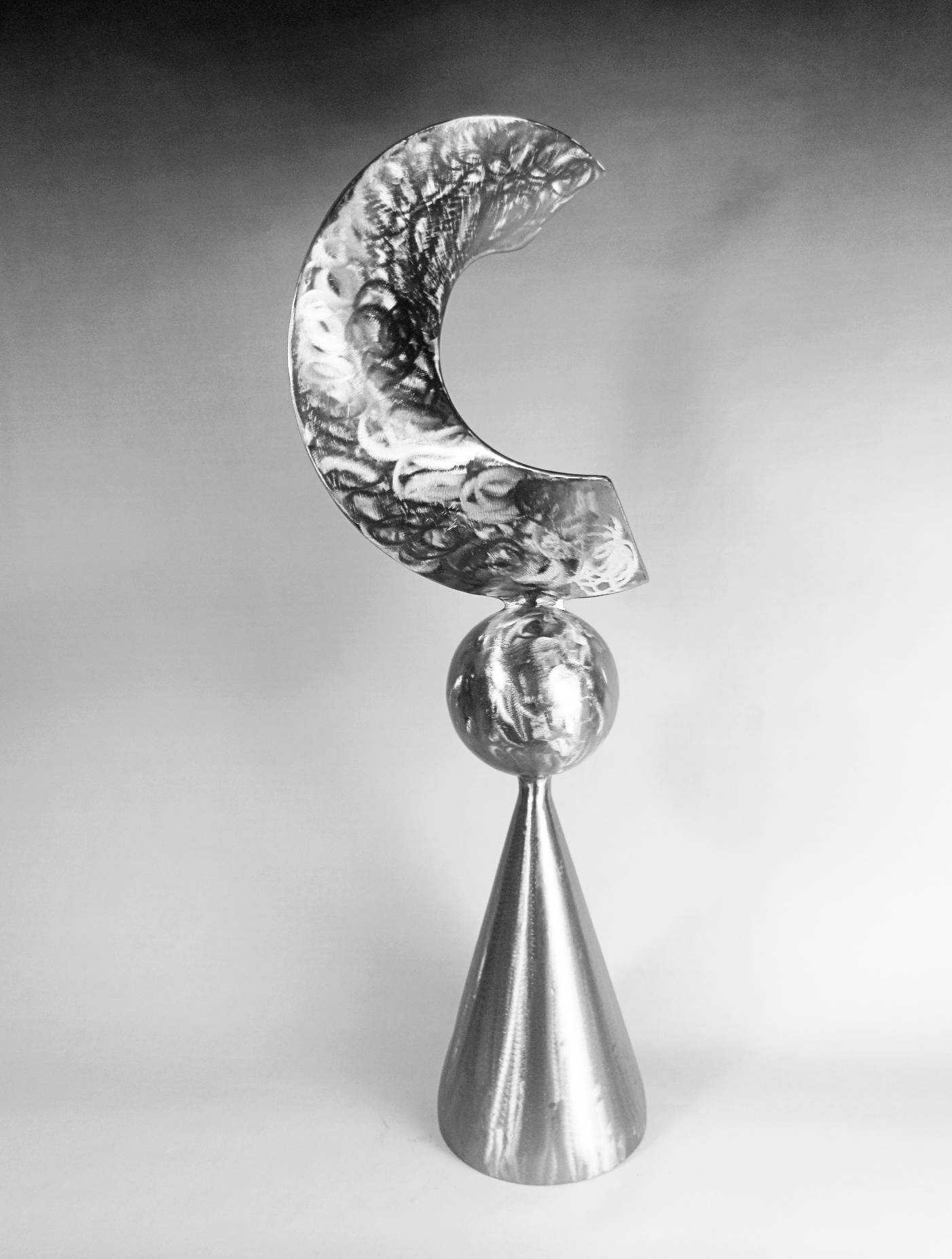 Metal sculpture from the Cone Series featuring a conical base, a spherical element, and a crescent-shaped form balanced vertically in a polished finish.