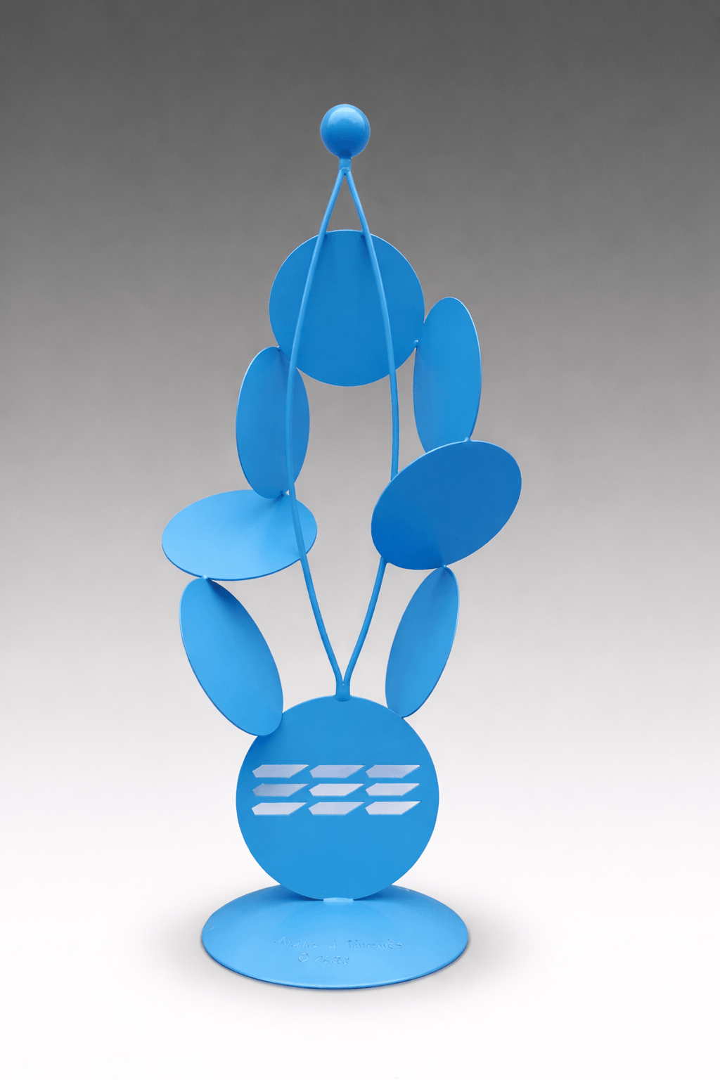 Turquoise metal sculpture composed of circular discs and slender supports arranged vertically, creating a balanced, airy structure with a sense of movement. By Michael Herold.